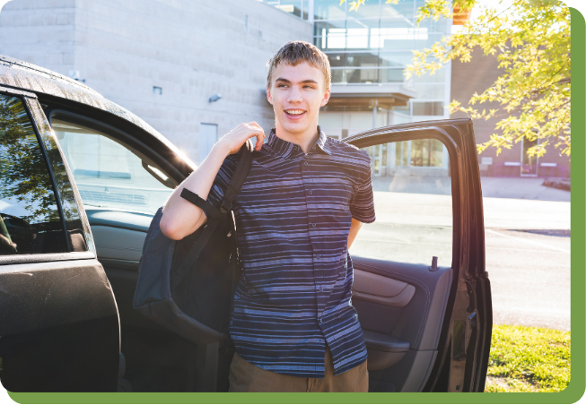 Teenage boy getting out of his car and putting a backpack on.